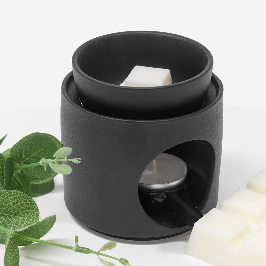 Elegant ceramic wax melt burner. The burner, featuring a matte black finish, includes a separate melting bowl and a tealight holder. 